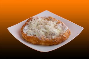 Traditional Transylvanian hungarian pastry, deep fried dough langos close up on restaurant table with cheese, sour cream and garlic.