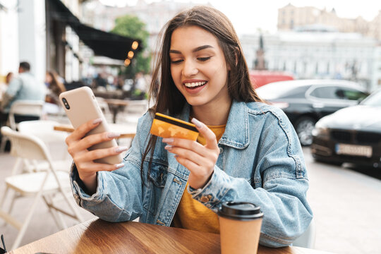 Image of smiling woman using cellphone and holding credit card