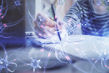 Neuron hologram over hands taking notes background. Concept of research and study. Double exposure