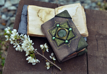 Decorated book and open diary with flowers on planks outdoors. Esoteric, gothic and occult background with magic objects, mystic and fairy tale concept