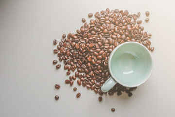 Naklejka premium The coffee cups and roasted coffee beans were placed on a white table by the window in the dining room, as the coffee beans were prepared for filming a drink menu. Top View and Copy Space