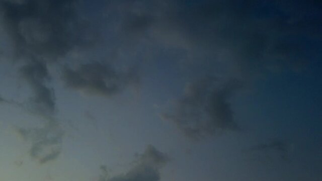 Time lapse: colorful to dark grey stormy wispy clouds slowly moving in eerie and spooky black sky, sunset, day to night