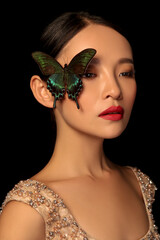 Asian woman decorating makeup face with butterfly taking makeup photo in black background