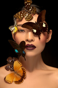 Asian woman decorating makeup face with butterfly taking makeup photo in black background