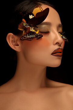 Asian woman decorating makeup face with butterfly taking makeup photo in black background