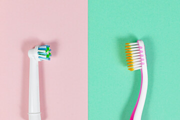 Comparison of electronic and traditional toothbrush side by side on pink and green background