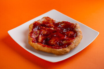 Traditional Transylvanian hungarian pastry, deep fried dough langos with jam close up on white plate