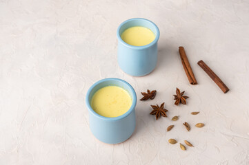 Two blue cups with traditional Indian masala chai tea with spices on a light background with copy space
