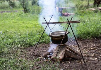 Bonfire and bowler on a background of nature. Summer camping in the park or outdoors