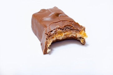 A piece of sneakerskie bitten on a white background teeth marks. One bar on a white background with bite marks. The malnourished snickers bar in macro