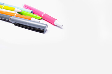 A large pile, the number of ballpoint pens of different colors on a white background. Pens for writing in close-up on a white background at an angle