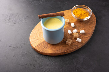 Ceramic blue cup with traditional Indian masala chai tea with cinnamon and sugar on cutting board. Top view with copy space