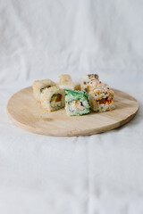 Sushi rolls on a wooden board with chopsticks on a white background. Stylish composition with sushi.