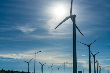 Close-up wind turbines or wind energy converter in sunny day with blue sky and white clouds