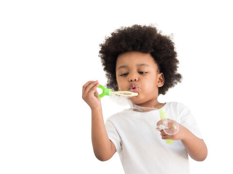 Dark skinned, mixed race African Asian boy blowing soap bubbles, white background at home
