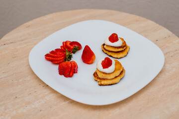Delicious homemade pancakes with strawberries on plate on a light background