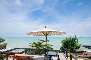 Wooden chair for sitting on the beach Set aside a seat for a resting point or a viewpoint near the beach with green trees On a day of turquoise waters and clear skies and beautiful clouds