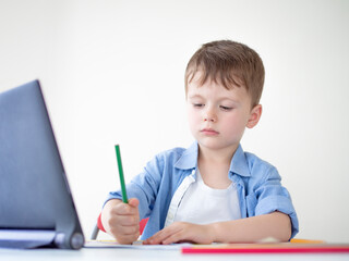 Online e-lessons for preschoolers. Kid looking video lesson on a tablet at home, learning to draw