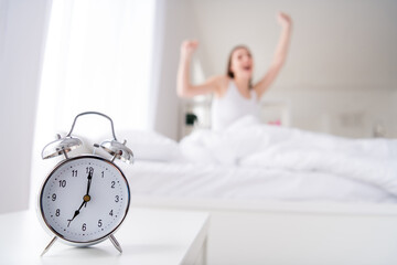 Obraz na płótnie Canvas Photo of charming young lady bed white sheets blanket clothes metal alarm clock ringing seven o'clock early morning yawning lazy worker yawning stretching bedroom indoors