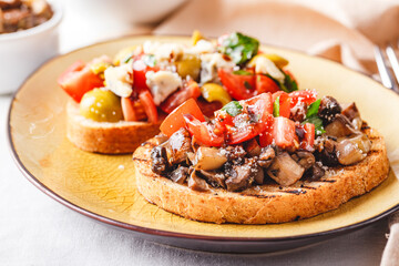 Delicious bruschettas with mushrooms, blue cheese, olives and tomatoes
