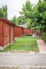 Wooden bungalows in a campsite with a lawn area.