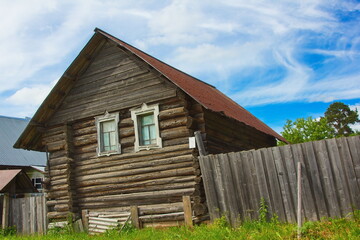 Fototapeta na wymiar Wooden rickety house in the countryside in the sunshine against a deep sky