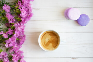 Fototapeta na wymiar cup of coffee, lilac flowers and macarons 