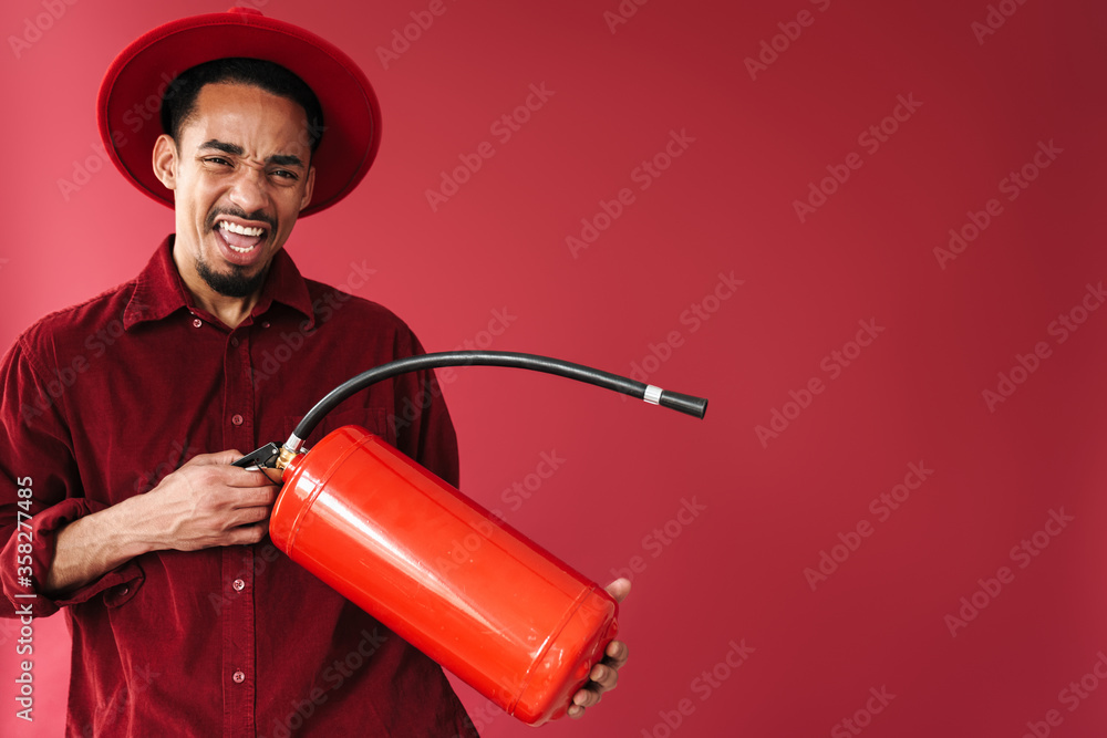 Poster Emotional young man holding fire extinguisher