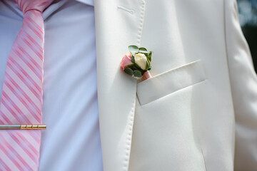 boutonniere of fresh rose flower on the groom's suit