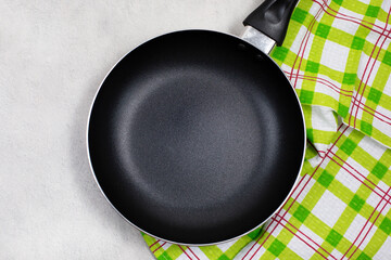 Empty black frying pan or skillet with green kitchen towel