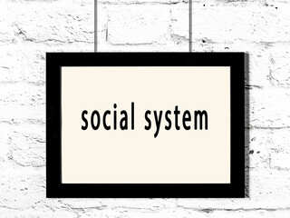Black frame hanging on white brick wall with inscription social system