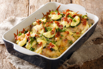 Light baked chicken casserole with zucchini, bacon and cheese close-up in a baking dish on the table. horizontal