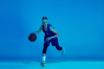 Desire to win. Young caucasian female basketball player training, prcticing with ball isolated on...