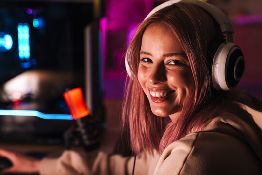 Image of happy girl in headphones playing video game on computer