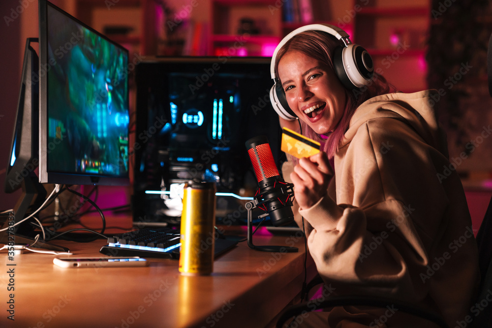 Wall mural image of girl holding credit card and playing video game on computer