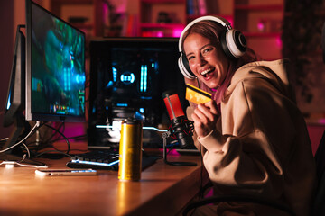 Image of girl holding credit card and playing video game on computer © Drobot Dean