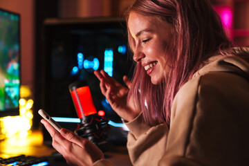 Image of girl using cellphone and smiling while playing video game