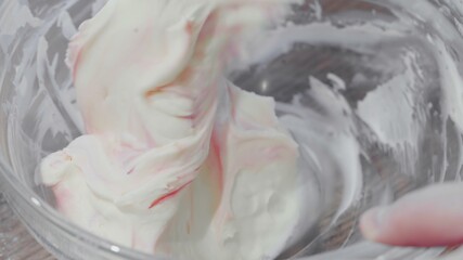 Mixing cream for cake in glass bowl.