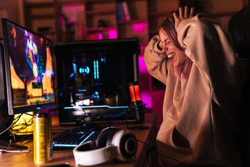 Image of displeased girl grabbing her head while playing video game