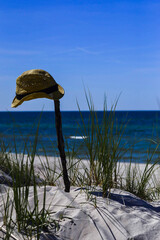 Straw hat hanged on a stick on a seaside beach.
