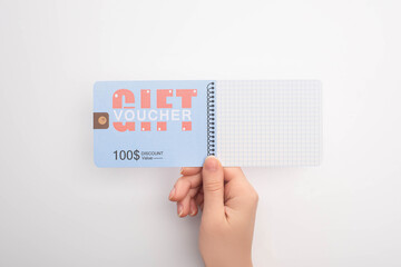 Cropped view of woman holding gift voucher with discount and value lettering on white background