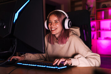 Image of excited girl smiling and playing video game on computer - obrazy, fototapety, plakaty
