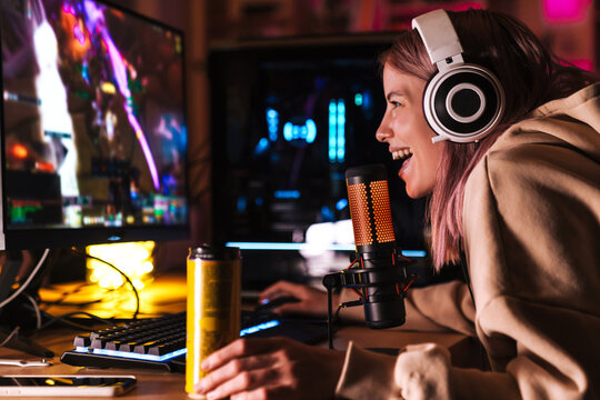Image of excited girl smiling and drinking soda while playing video game