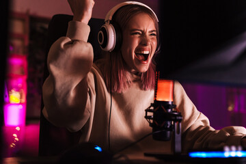 Image of girl making winner gesture and playing video game on computer