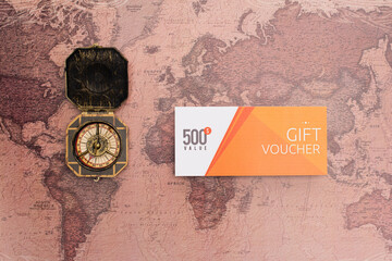 Top view of gift voucher with 500 value lettering and compass on map surface