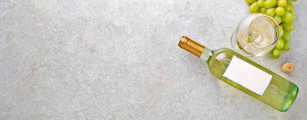 White wine in a glass, bottle, grapes and cork on a gray stone table. - obrazy, fototapety, plakaty