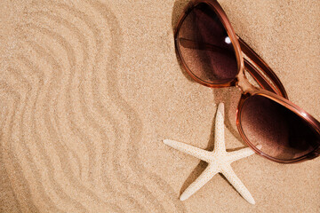 Fototapeta na wymiar Summer textured background with waves of sand, sea star and pink sunglasses. Copy space