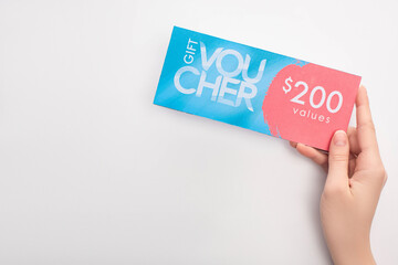 Top view of woman holding gift voucher with 200 values lettering on white background - obrazy, fototapety, plakaty