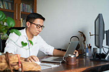 adult Asian businessman working from home serious and thinking