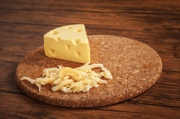 piece of Cheese and Cheddar Cheese grated on old vintage Cooking wooden table. Mozzarella Cheese background Texture and Copy space